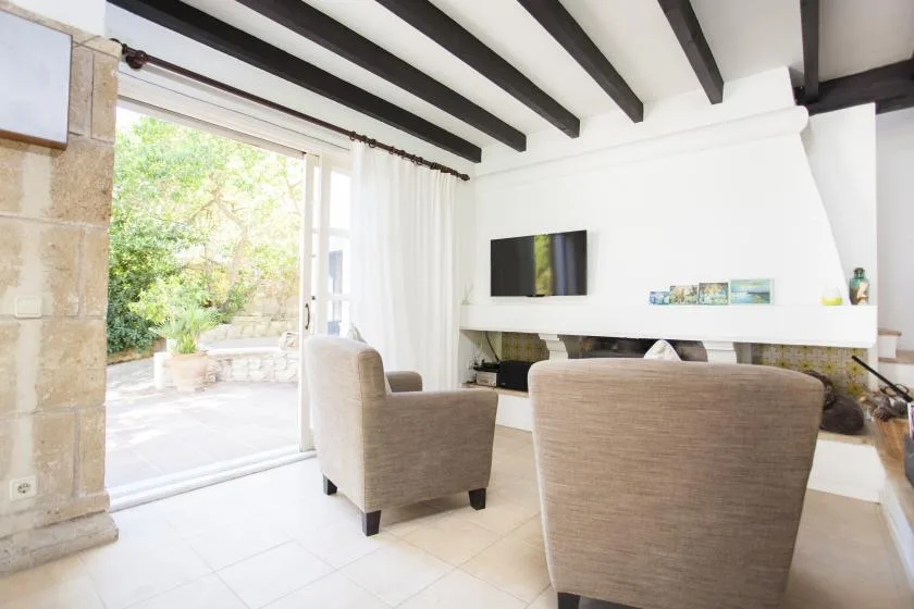 A bright living room with seating arranged in front of a fireplace and television.