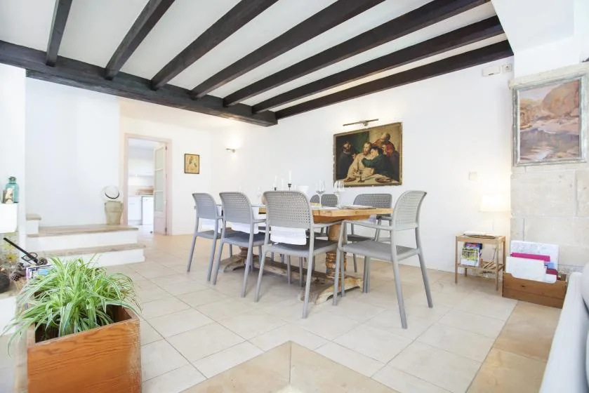 A dining area with a table and chairs beneath dark ceiling beams.
