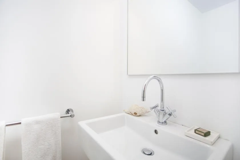 A bathroom sink with a curved faucet and a hand towel on a nearby rail.