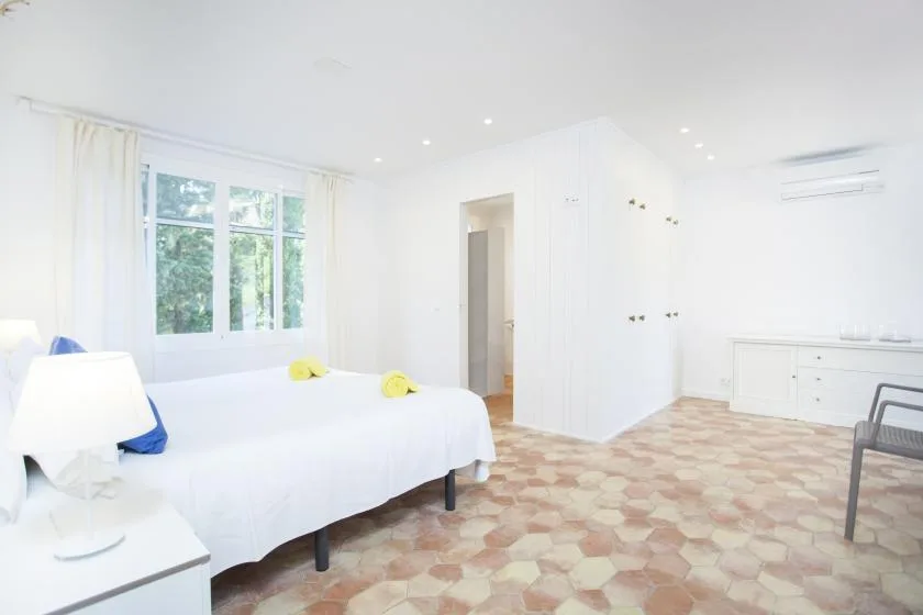 A bright bedroom with a bed, a window, and a built-in wardrobe.