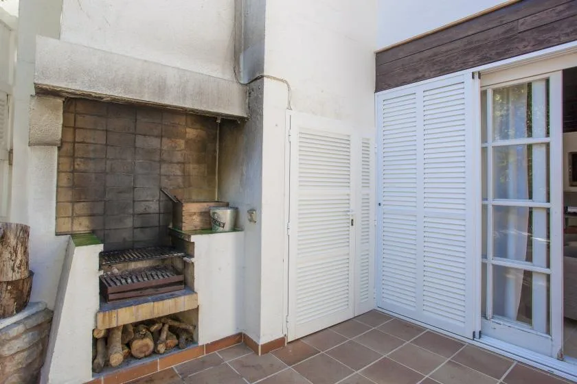 A tiled barbecue area sits beside white louvered doors and a glass-paned opening.
