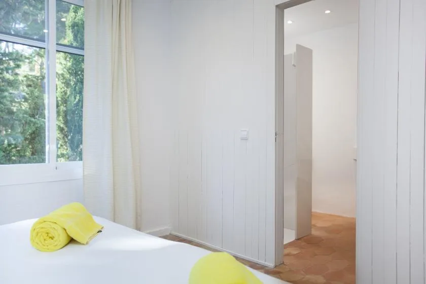 A bright bedroom with a bed beside a window and an open doorway.