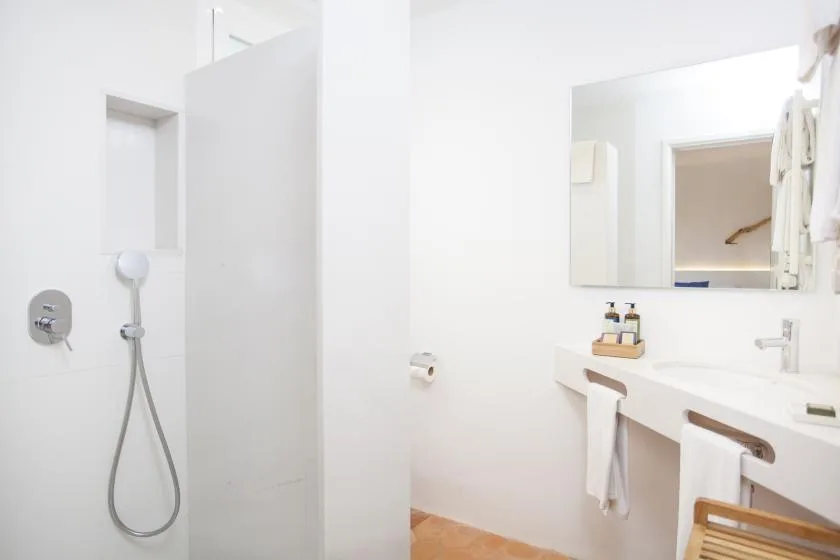 A bright bathroom with a shower and a long sink counter.
