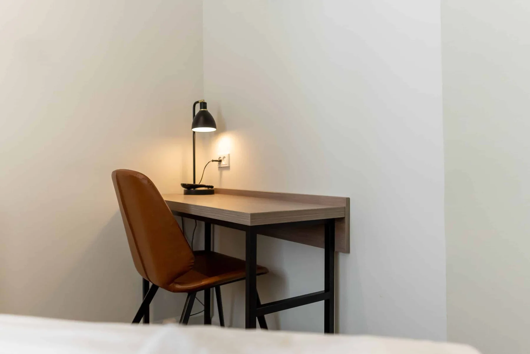Desk, chair and reading lamp in a hotel room.