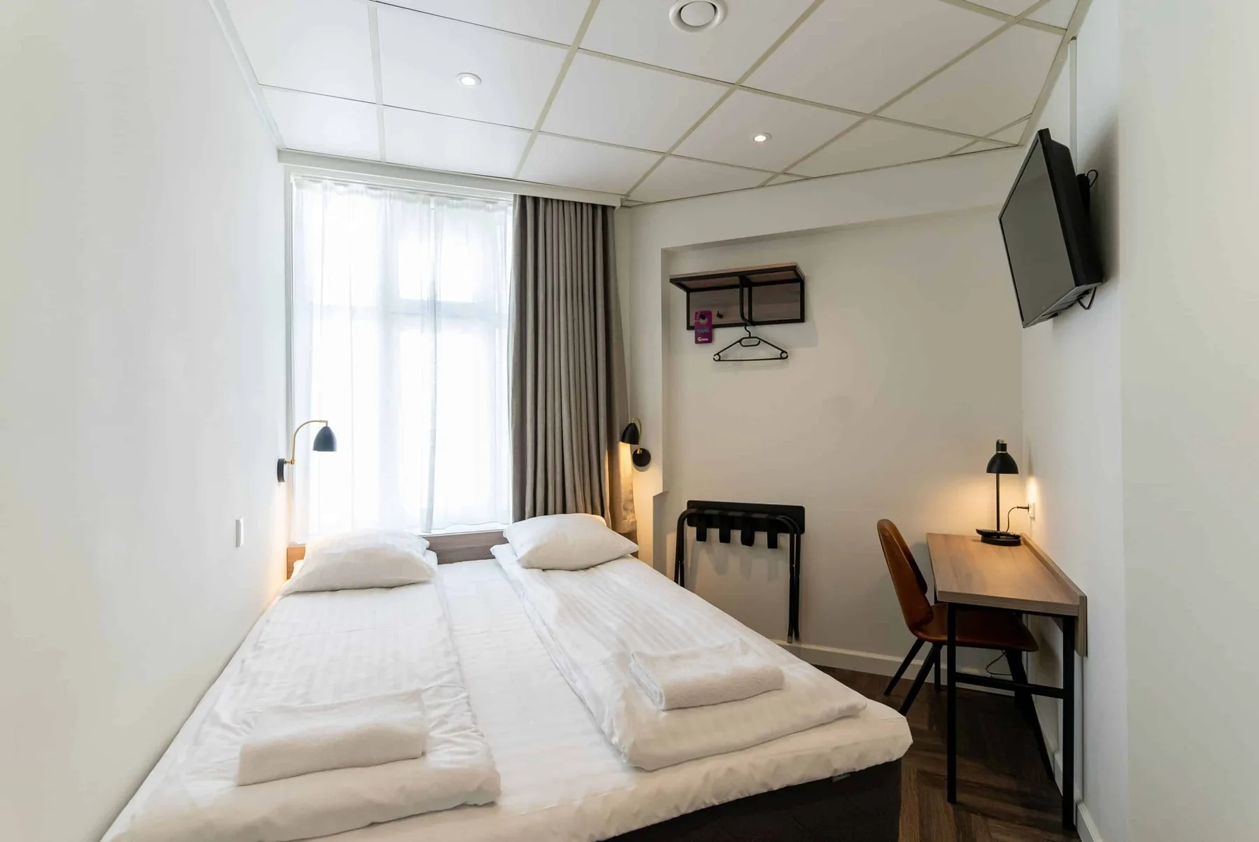 Standard double room with a double bed, work area and TV.