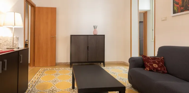 A living room with a dark sofa, coffee table, and patterned rug.