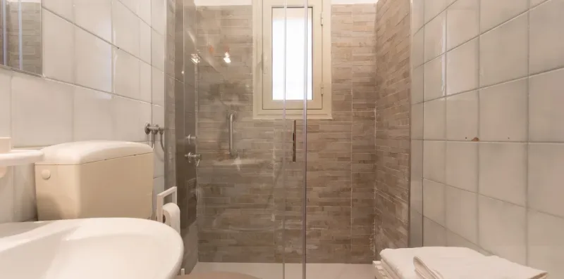 A tiled bathroom with a glass shower and a sink.