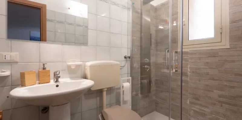 A tiled bathroom with a sink, toilet, and glass shower.