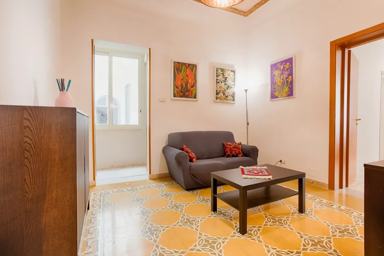 A living room with seating, a coffee table, and colorful patterned flooring.