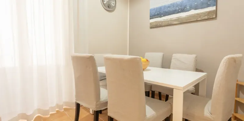 A dining area with a white table and upholstered seating.