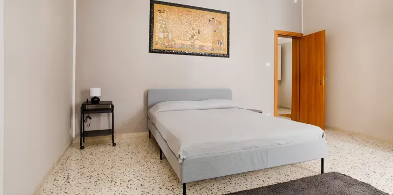 A bedroom with a bed, bedside table, and an open wooden door.