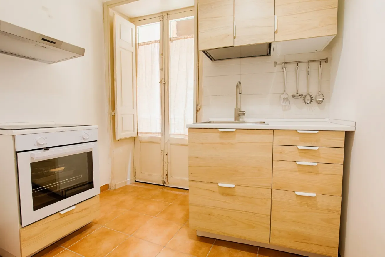 A bright kitchen with light wood cabinets and a built-in oven.