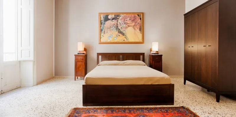 A bedroom with a wooden bed, matching bedside tables, and a large wardrobe.