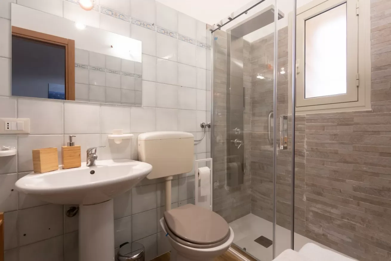 A tiled bathroom with a sink, toilet, and glass shower.