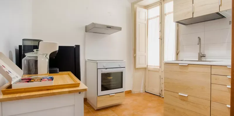 A bright kitchen with light wood cabinets, a countertop, and a built-in oven.