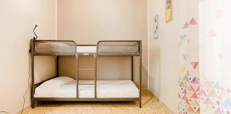 A bedroom with a metal bunk bed and colorful wall decorations.