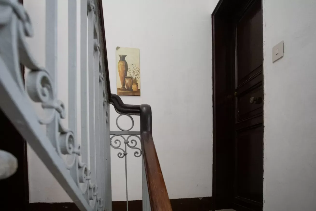 A stairway with decorative metal railings leads toward a dark wooden door.