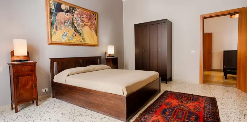 A bedroom with a double bed, bedside tables, and a patterned rug.