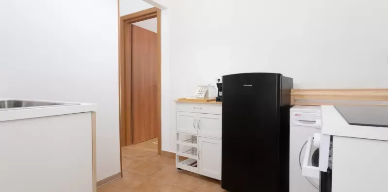 A laundry area with a black refrigerator, washer, and white cabinets.