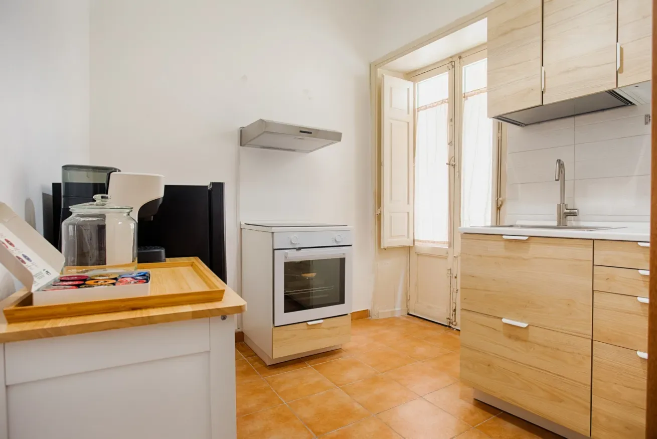 A bright kitchen with light wood cabinets and a built-in oven.