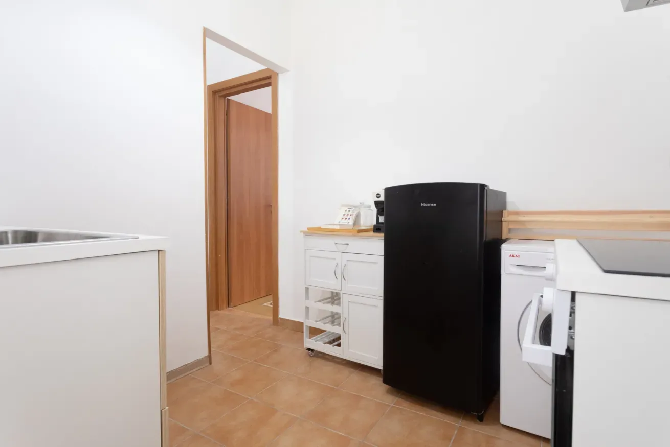 A compact kitchen with white cabinets, a black refrigerator, and a washing machine.