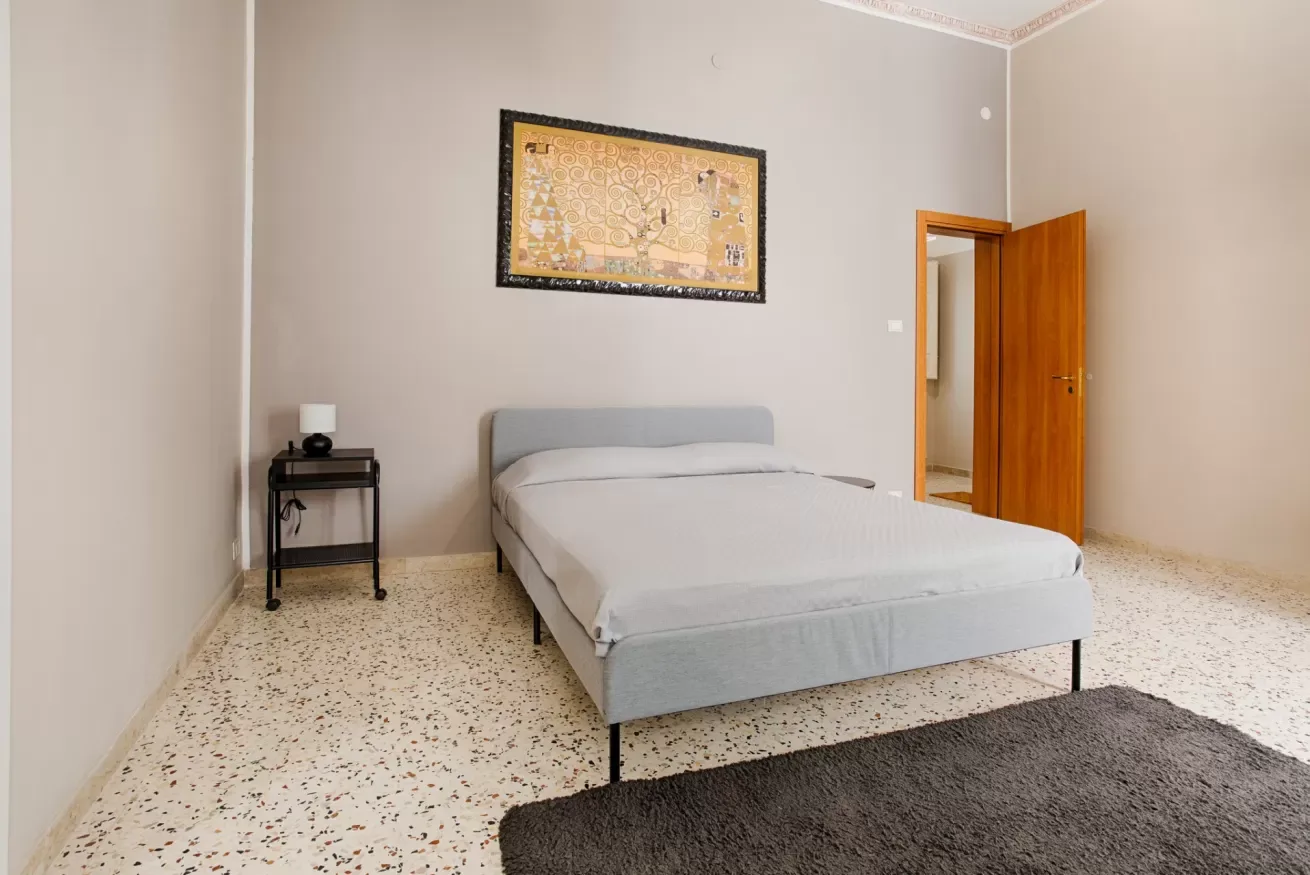 A bedroom with a bed beneath framed wall art and an open wooden door.