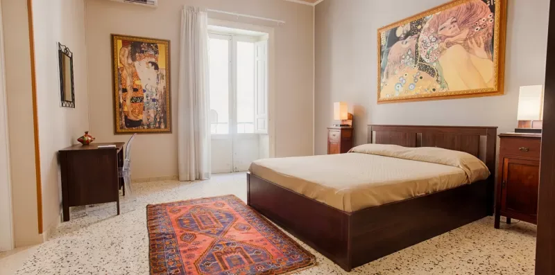 A bedroom with a large bed, bedside tables, and colorful wall art.