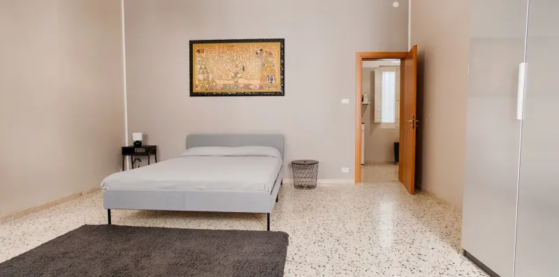 A bedroom with a bed, framed wall art, and an open doorway.