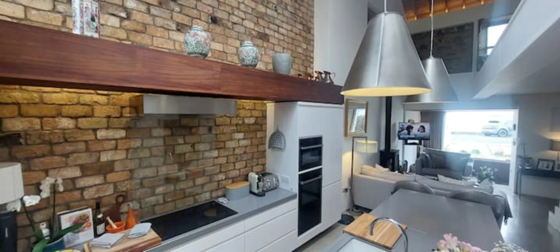 Una cocina moderna se abre a una sala de estar con paredes de ladrillo visto.
