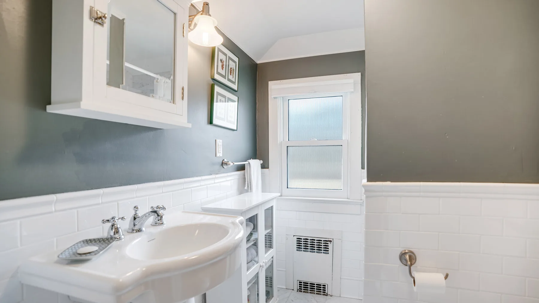 A bathroom with a sink, tiled walls, and a frosted window.