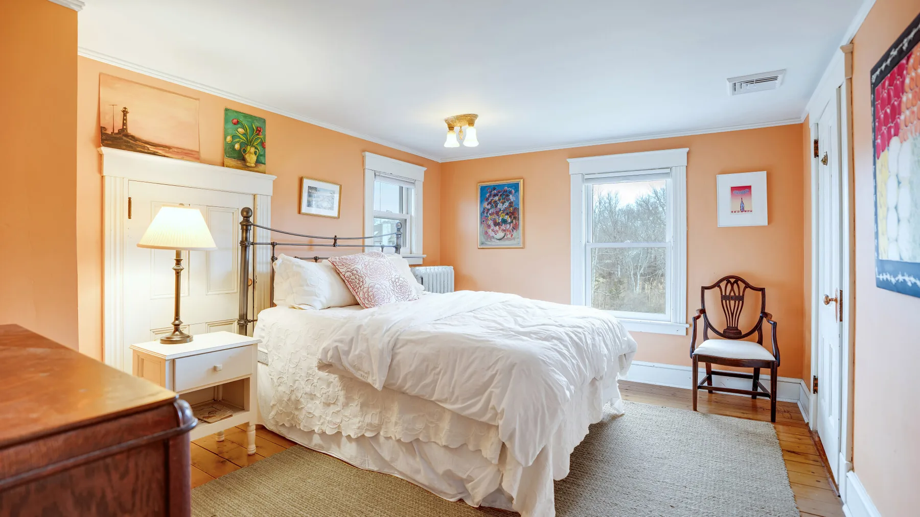A bedroom with a bed, bedside table, and windows.