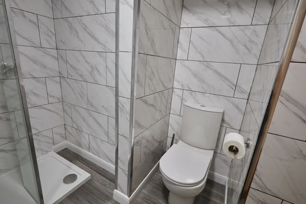 A tiled bathroom with a toilet and a glass-enclosed shower.