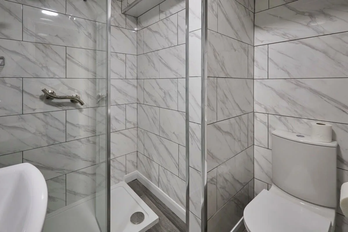 A tiled bathroom with a shower and toilet.