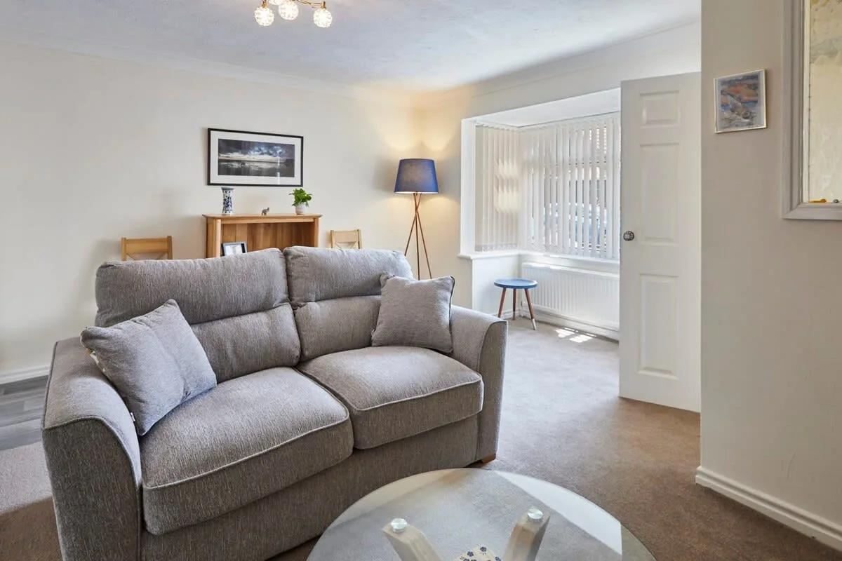 A living room with gray seating and a bright window.