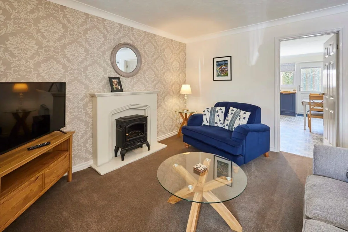 A living room with blue seating, a television, and a fireplace.
