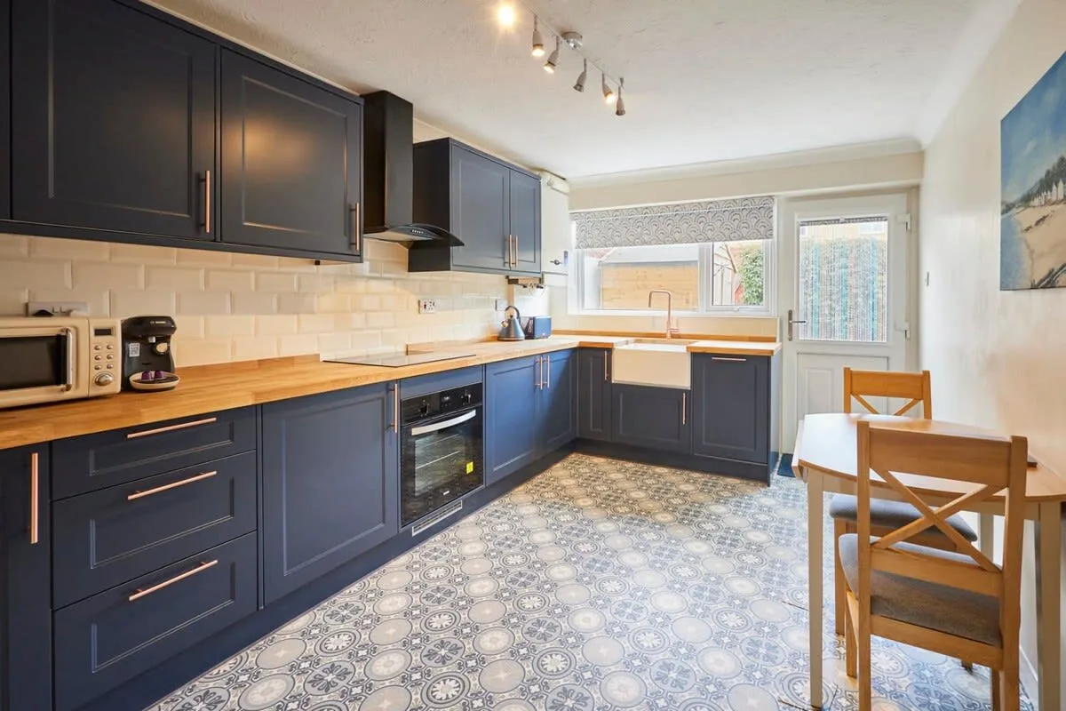A modern kitchen with dark cabinets, wood countertops, and a small dining table.