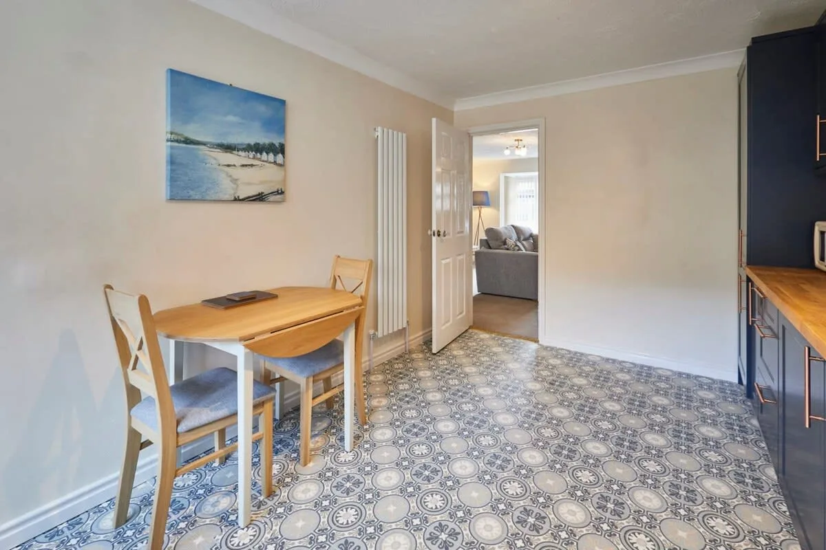 A dining area with a wooden table and chairs beside a patterned floor.