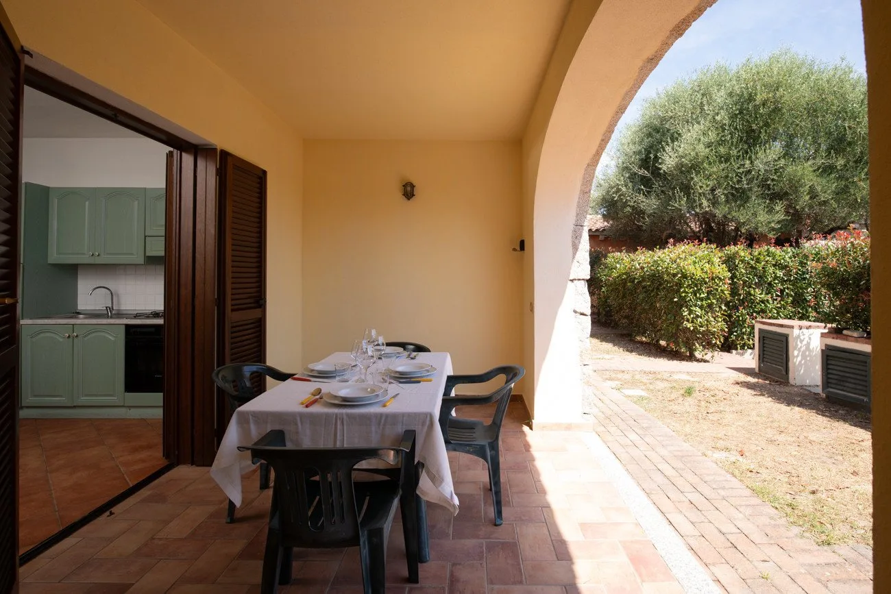 Un patio cubierto con una mesa de comedor junto a una vista abierta del jardín.