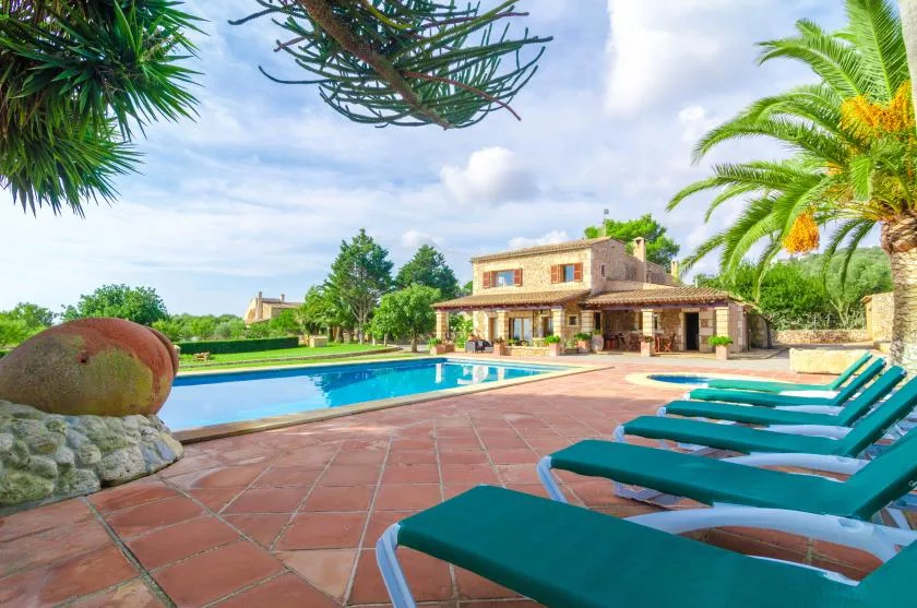 Una piscina y asientos junto a una casa de piedra.