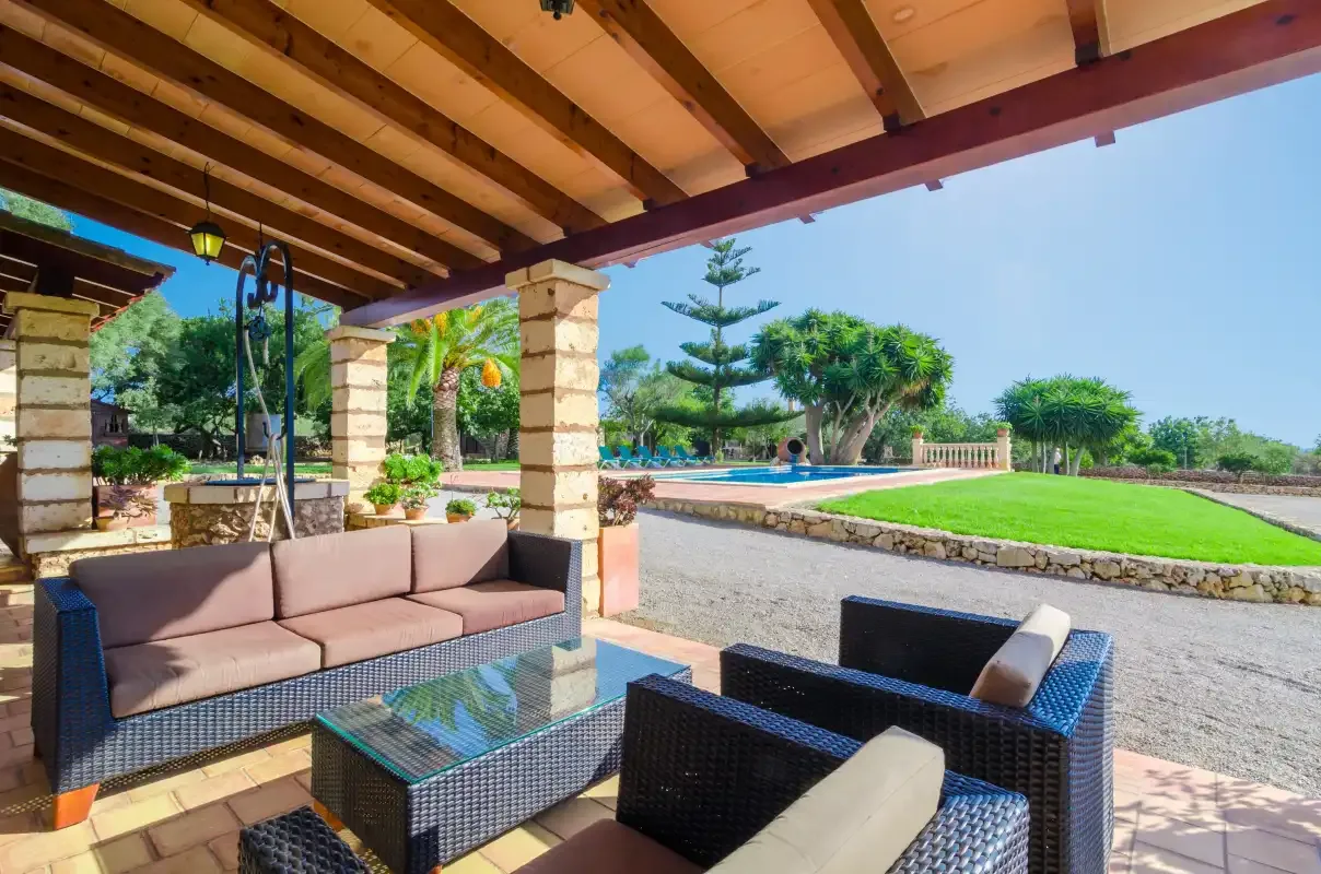 Un patio cubierto con asientos da a un césped y una piscina.