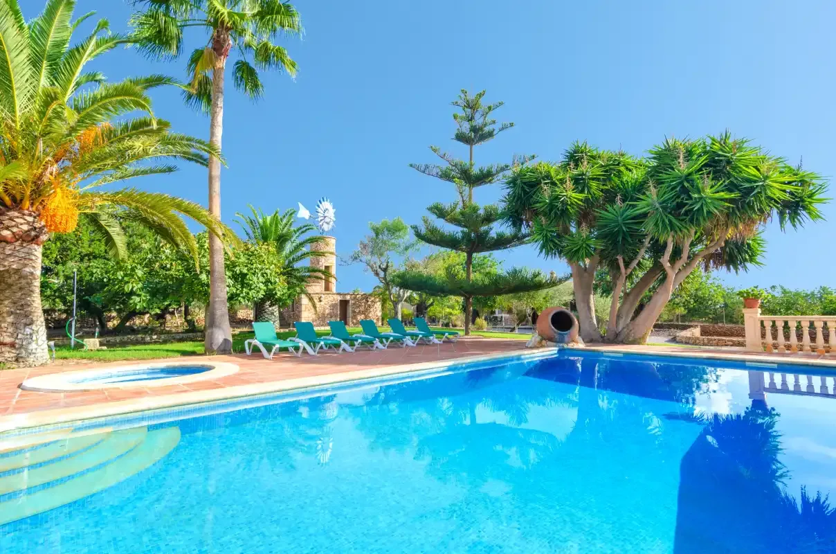 Una piscina rodeada de palmeras y asientos al aire libre.
