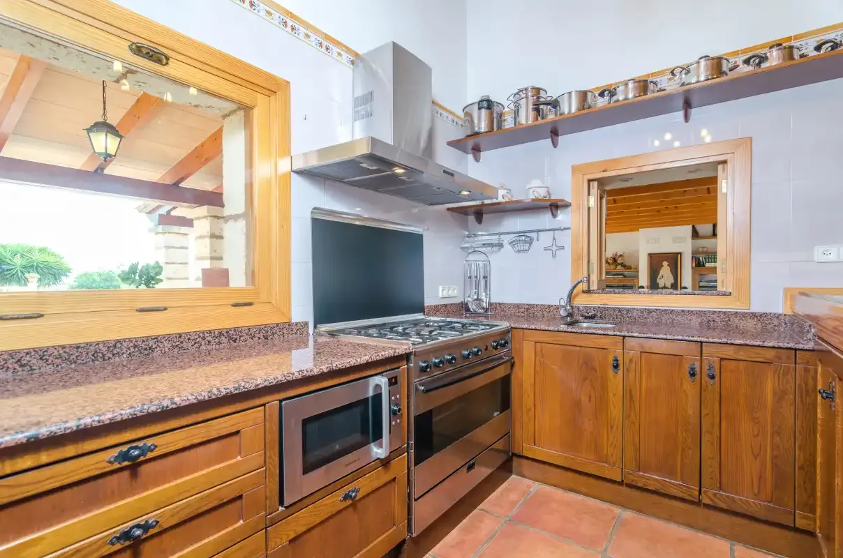 Cocina con armarios de madera, encimeras de azulejos y una cocina de gas.