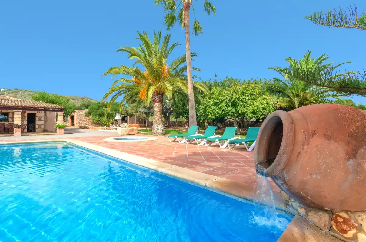 Una piscina al aire libre está rodeada de palmeras y asientos para relajarse.