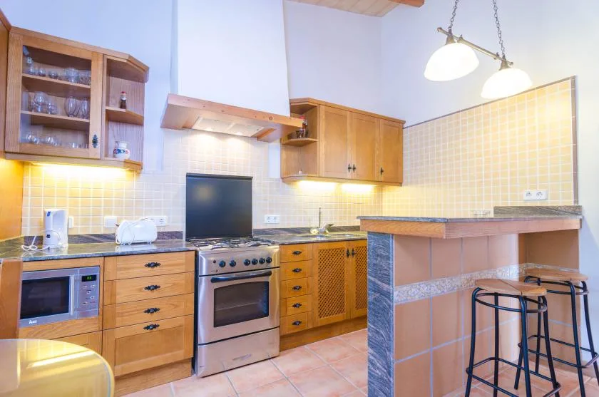 Una cocina con armarios de madera, una estufa y una barra con taburetes.