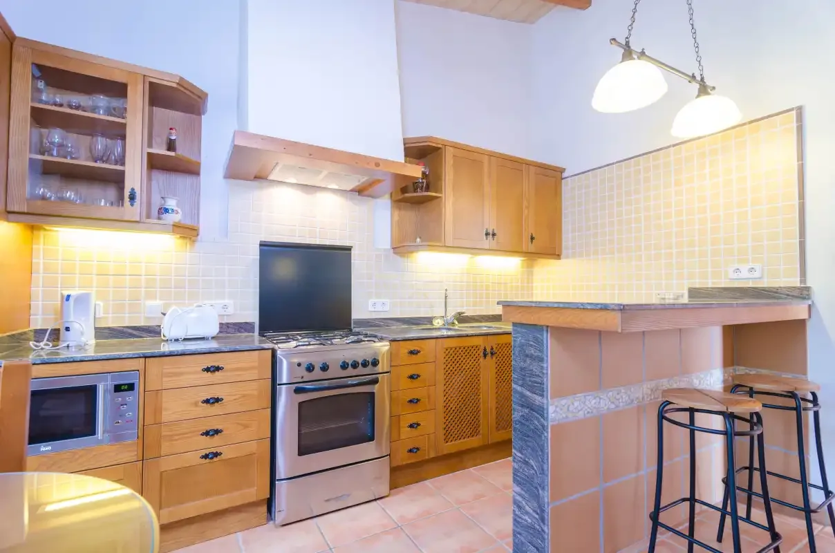 Una cocina con armarios de madera, un horno y una barra.