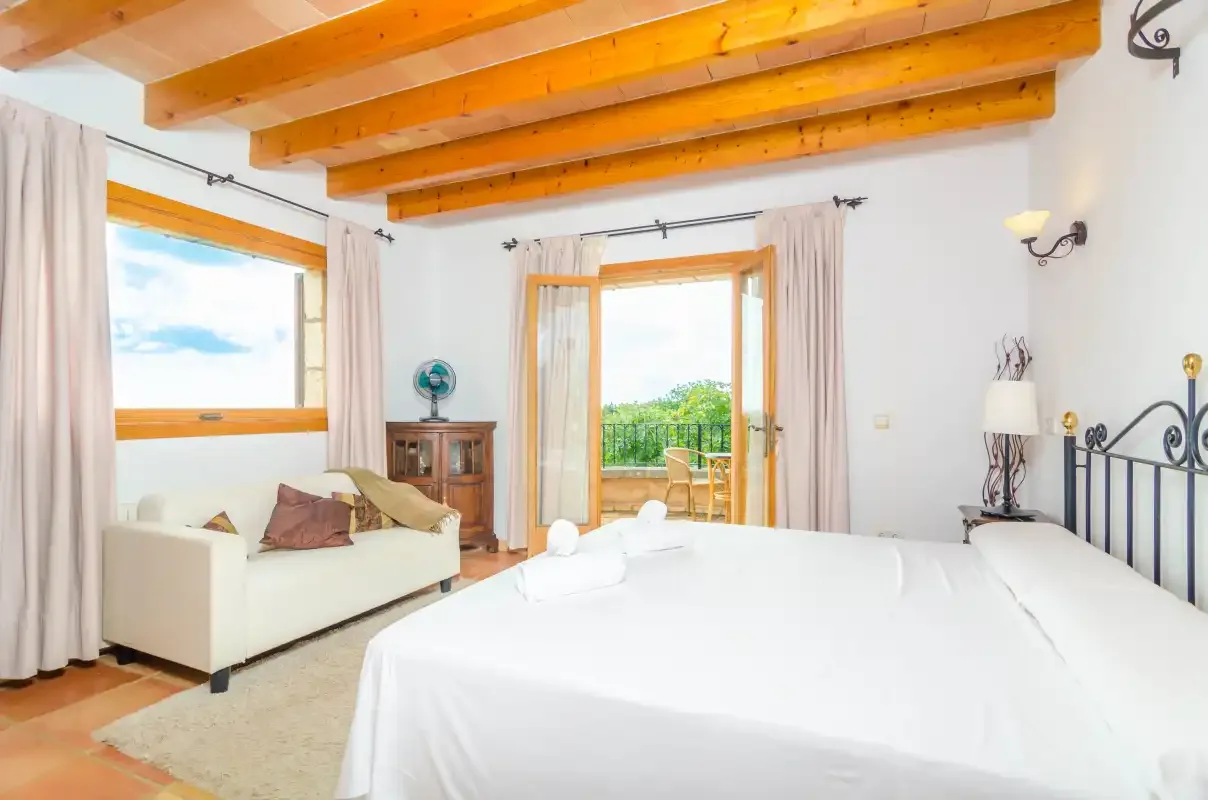 Un dormitorio luminoso con una cama grande y ventanas que dan a la vegetación.