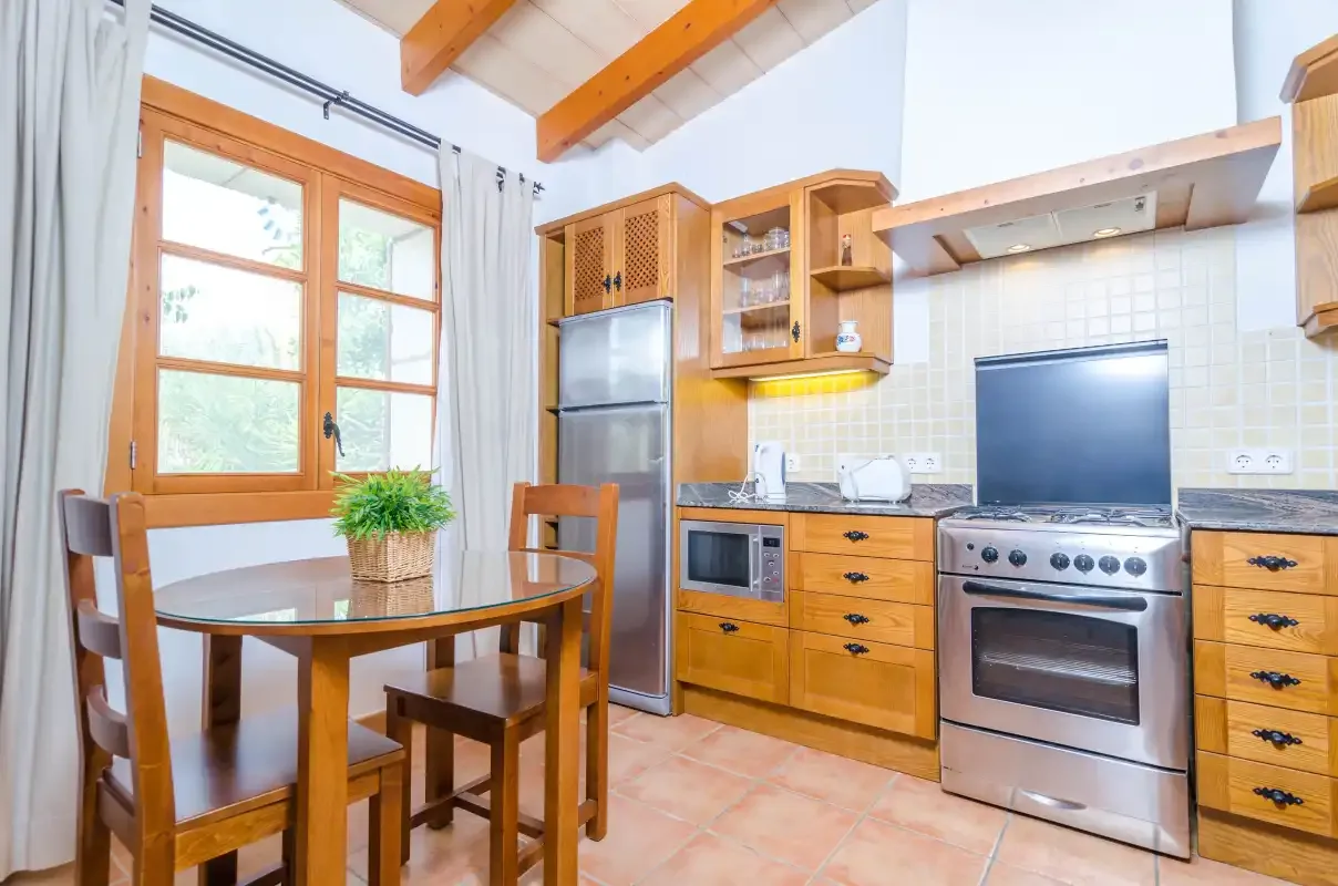 Una cocina luminosa con armarios de madera y una mesa de comedor junto a la ventana.