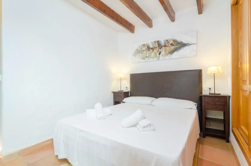 Un dormitorio con una cama grande, mesas de noche y vigas expuestas en el techo.