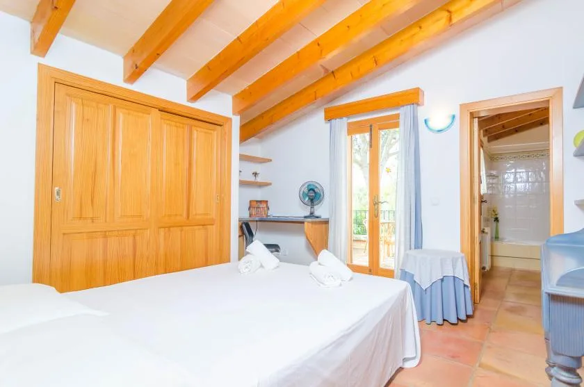 Un dormitorio luminoso con una cama grande, un armario de madera y puertas de vidrio.