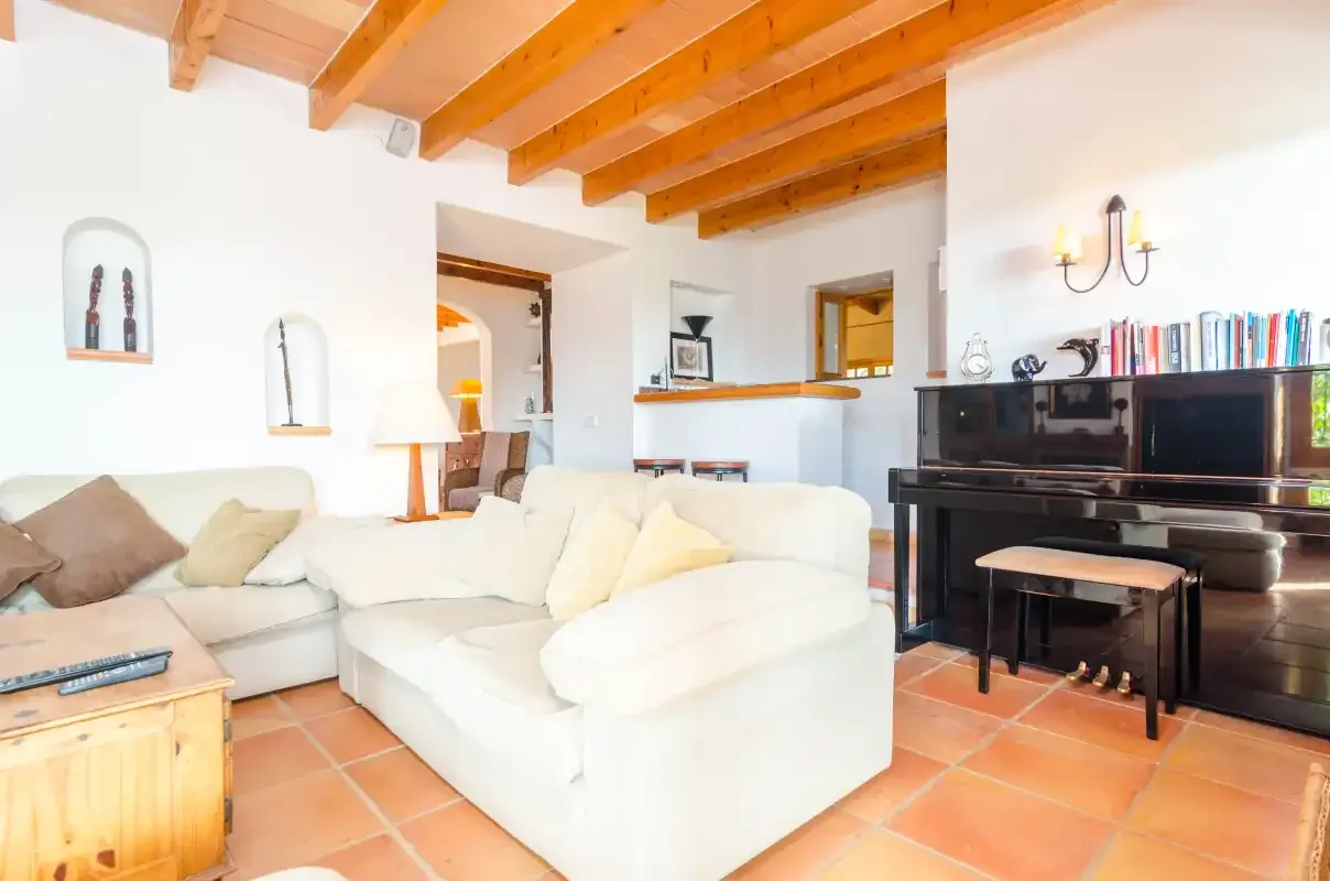 Sala de estar con asientos blancos y un piano vertical negro.